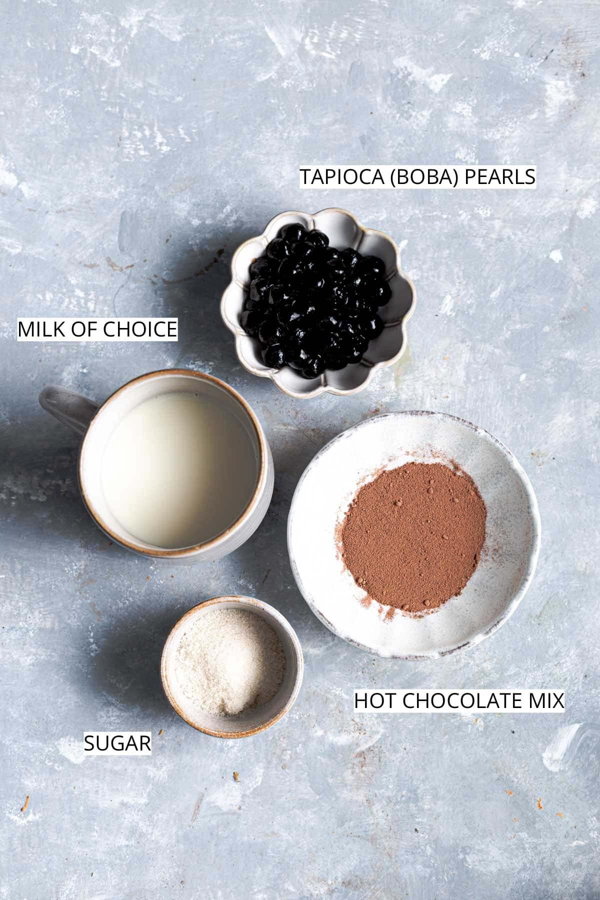 All the ingredients needed to make boba tea placed on a flat surface.