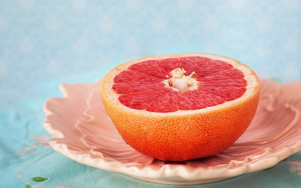Half a pink grapefruit placed on a textured pink plate.