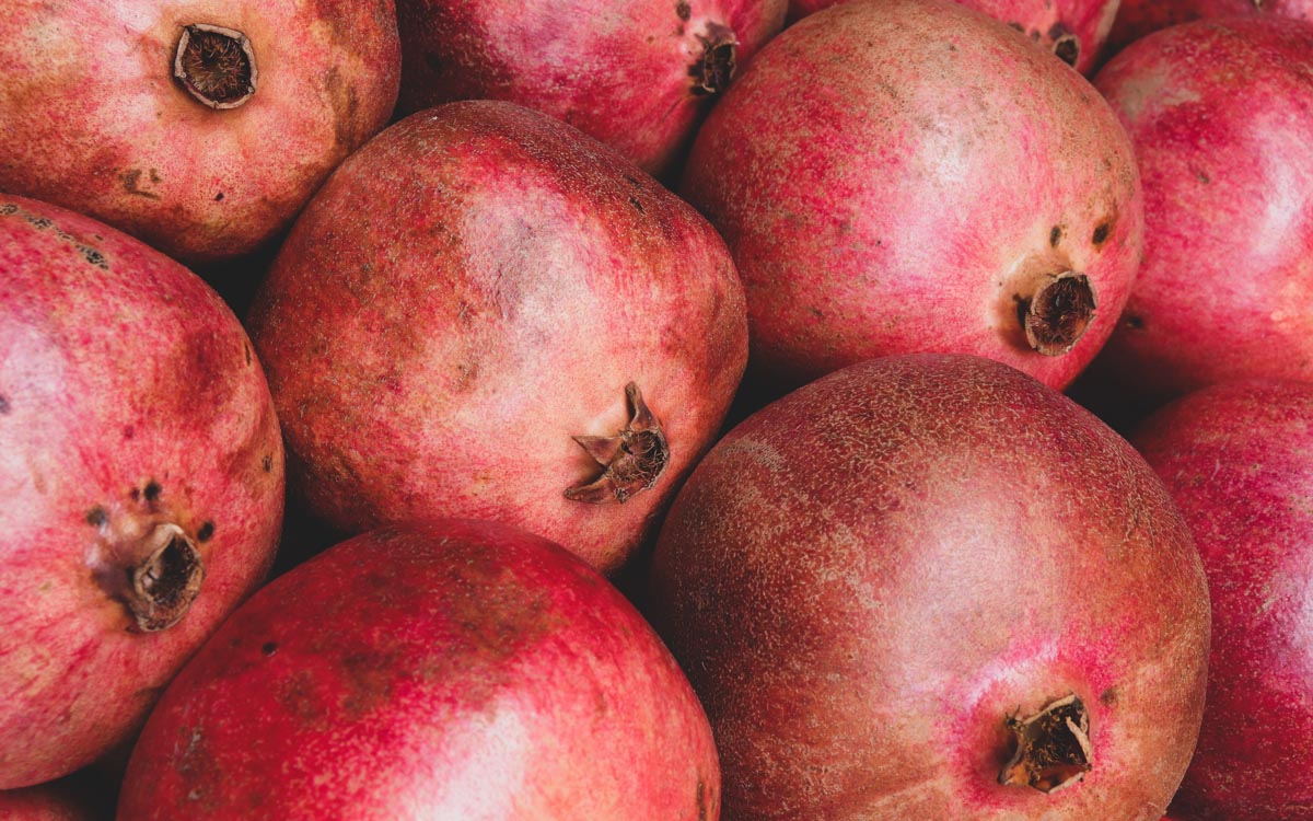 A close-up image of many pomegranates placed next to each other. 