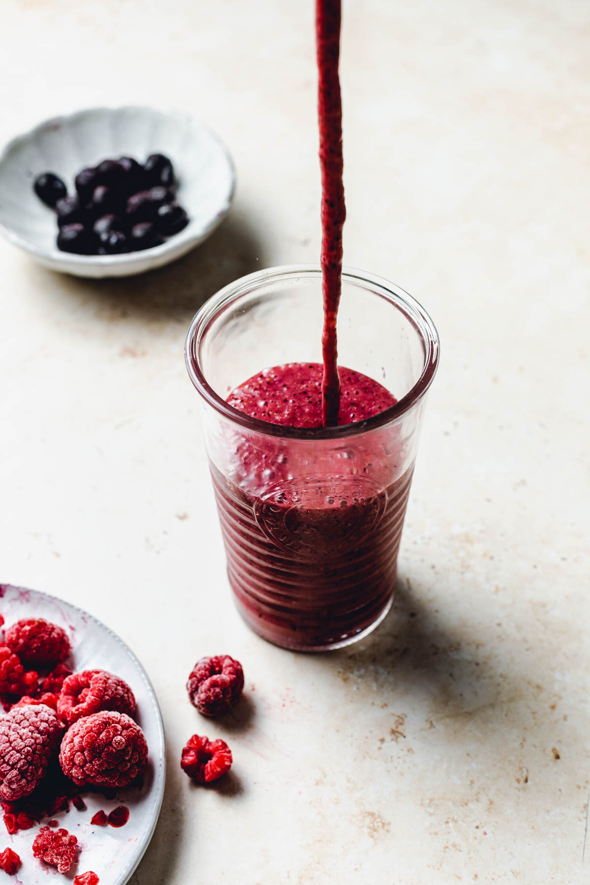 A side view of deep red smoothie being poured into a ribbed glass.