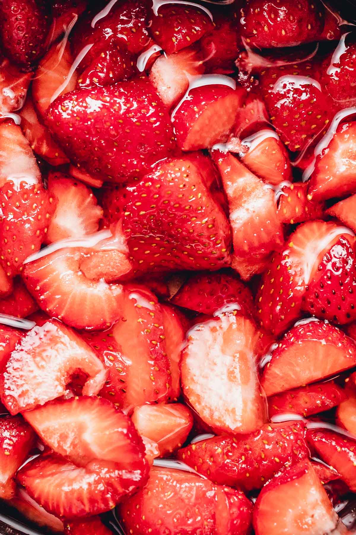 A close-up image of sliced strawberries in water.