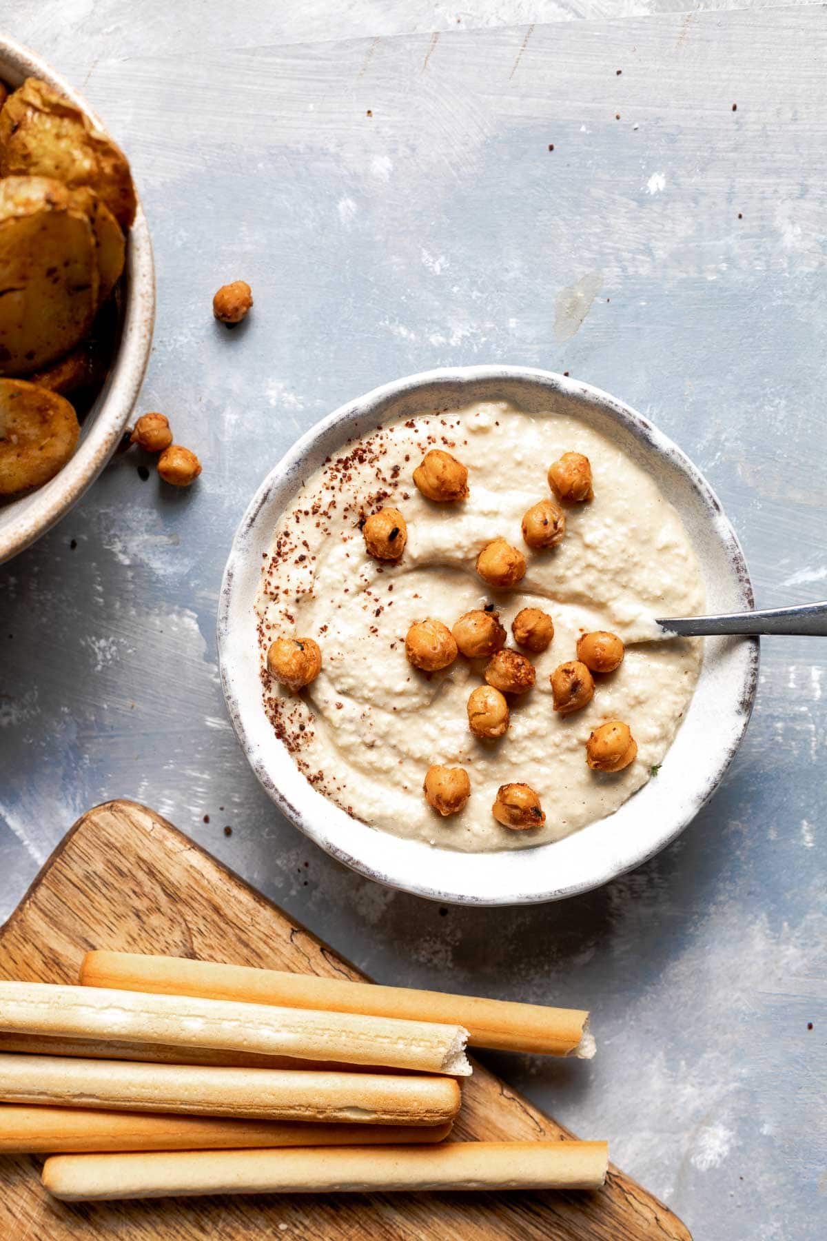 A bowl of hummus with roasted chickpeas on top.