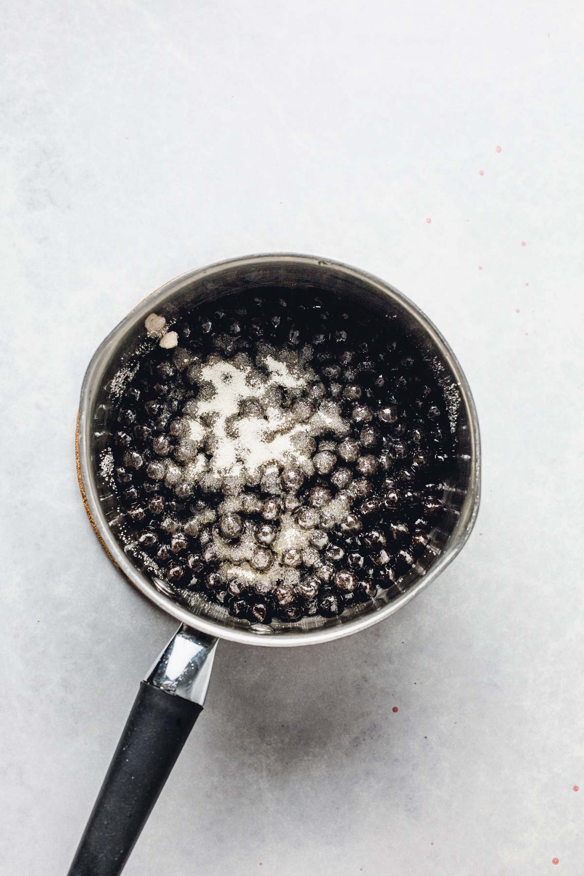 A small saucepan filled with cooked tapioca pearls and sugar on top.