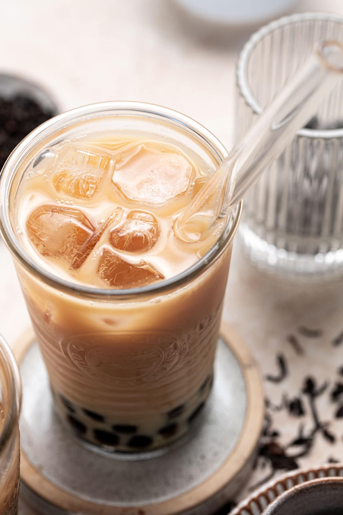 A side view of Oolong milk tea with a glass straw inserted in the middle.