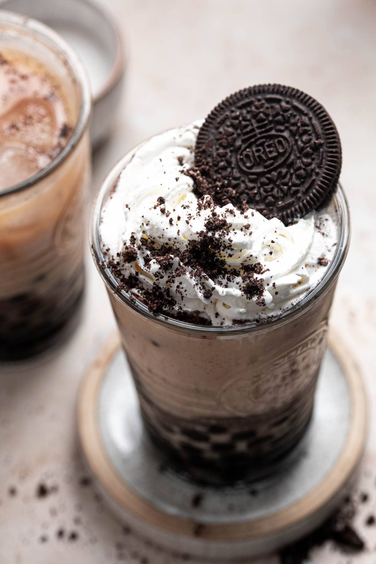 A glass filled with Oreo bubble milk tea and topped off with whipped cream.