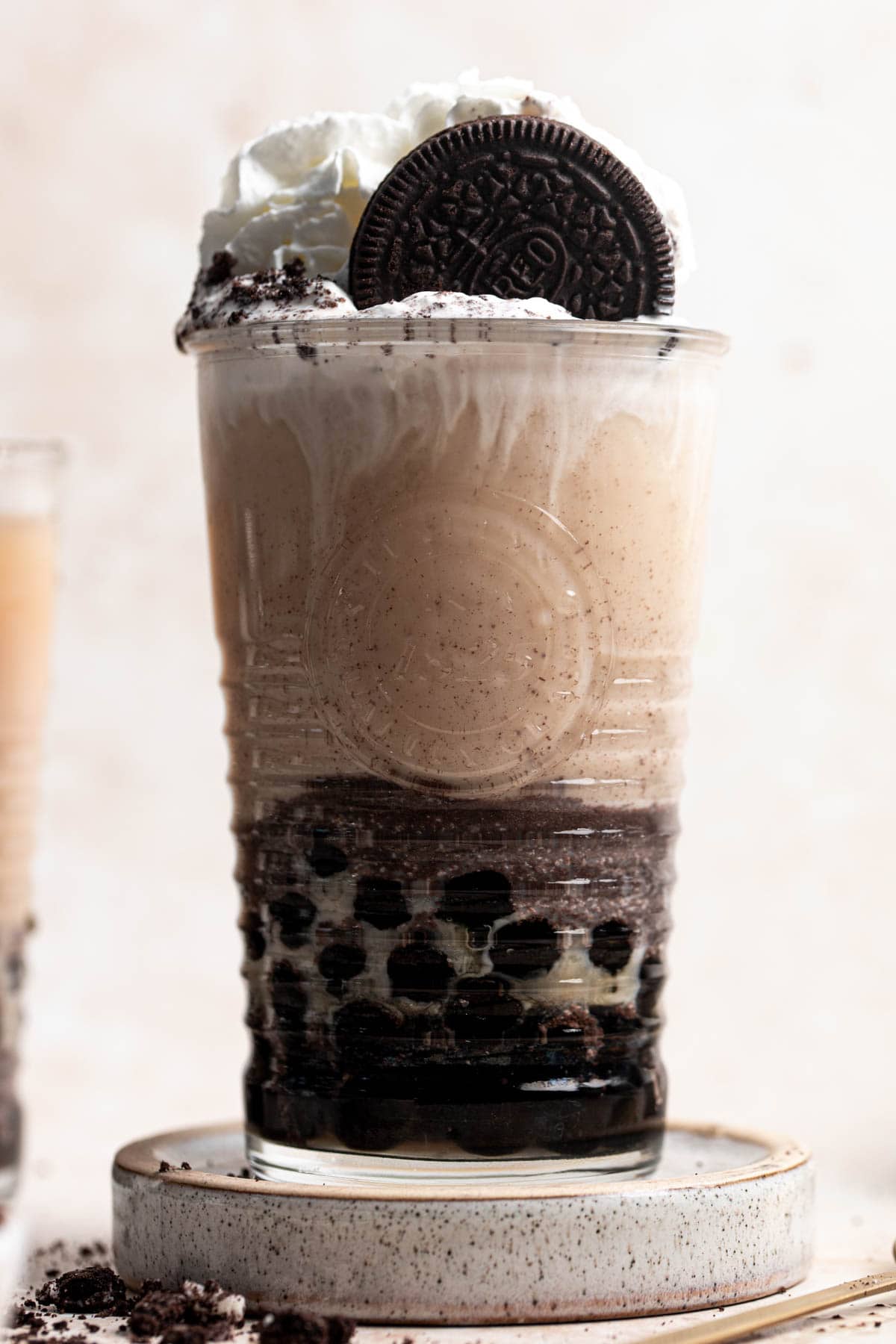 A close-up image of a glass of Oreo milk tea topped off with cream.