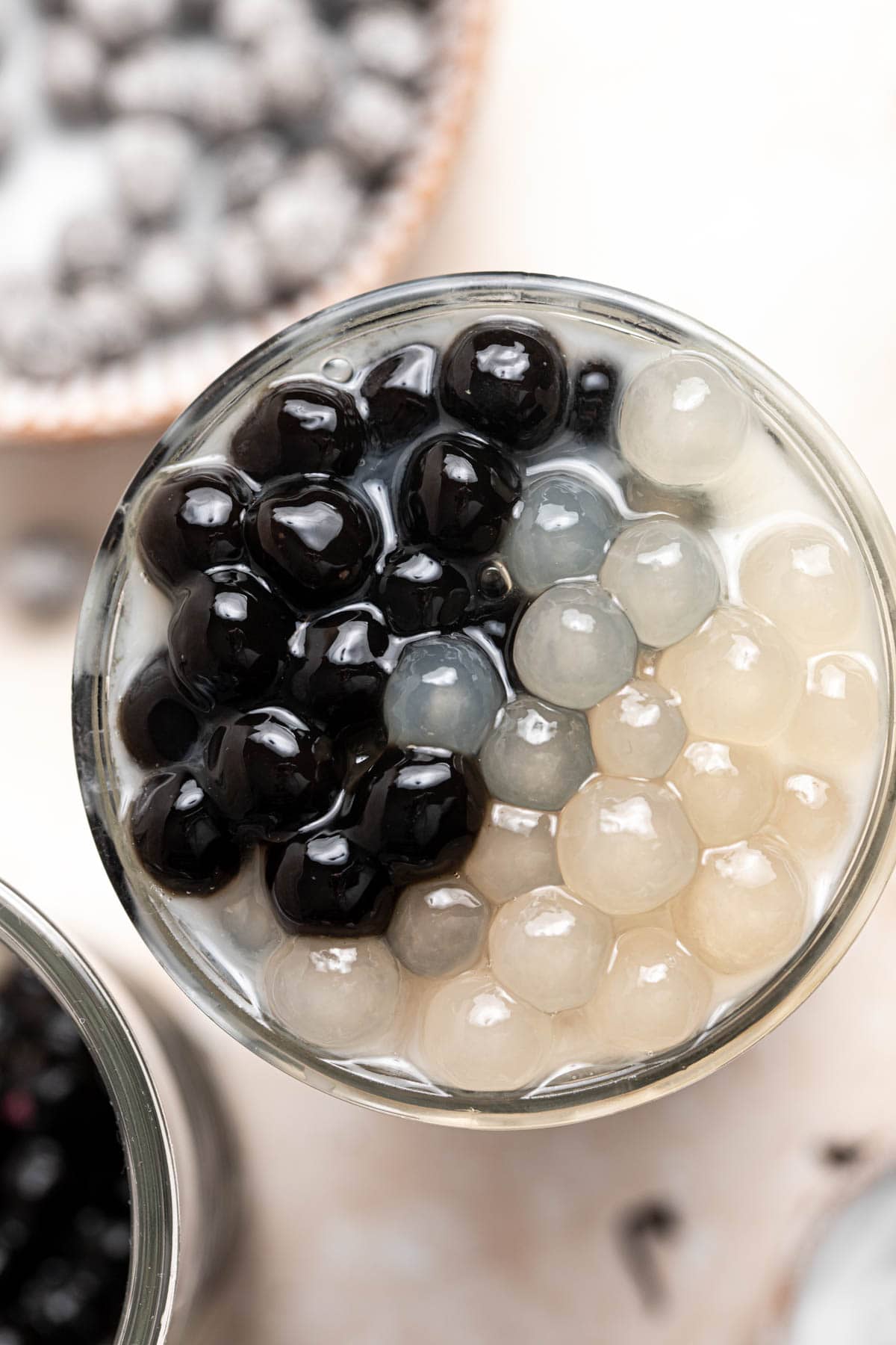 A close-up overhead view of a glass filled with white and black tapioca pearls.