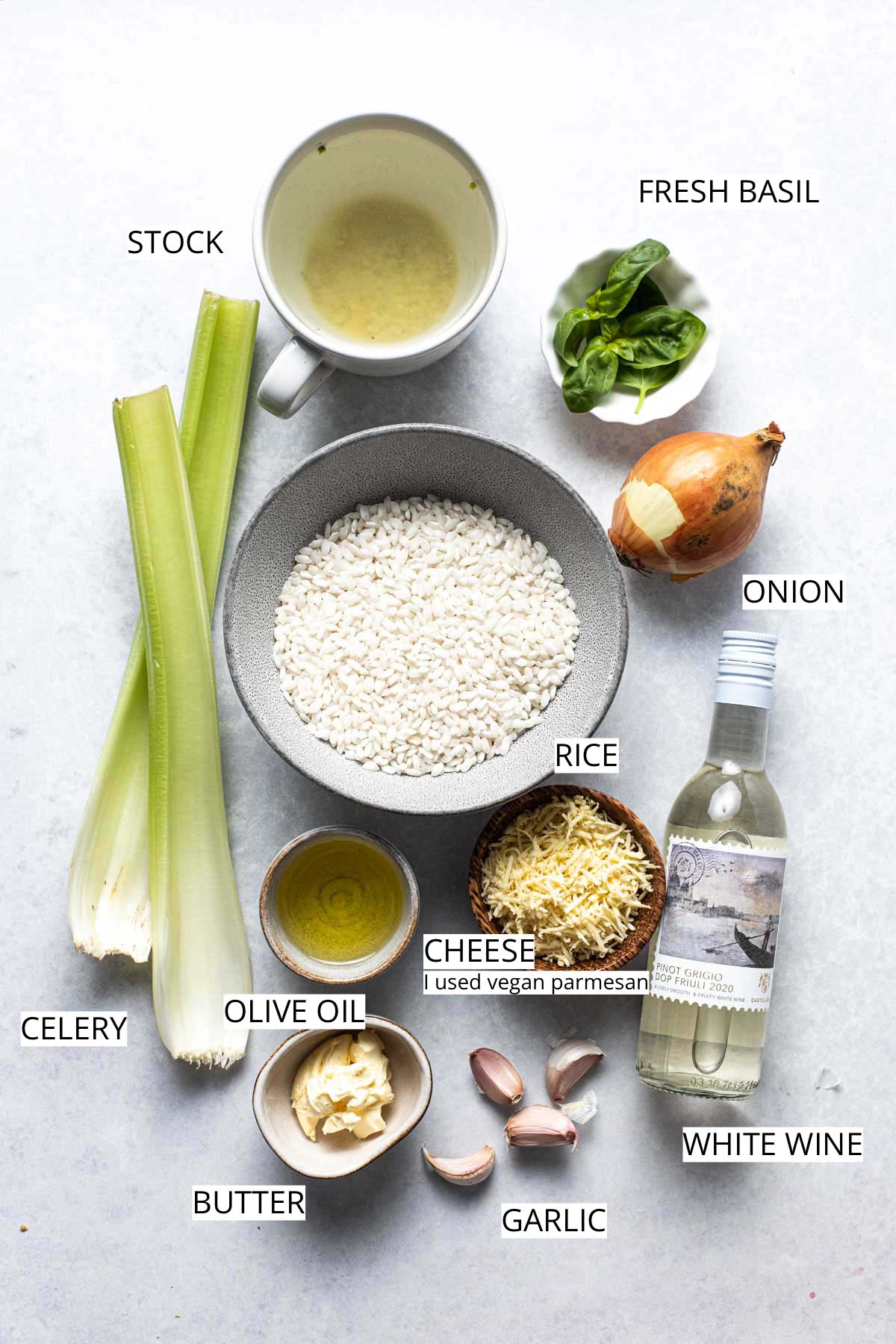 All ingredients needed to make risotto laid out in bowls on a flat grey surface.