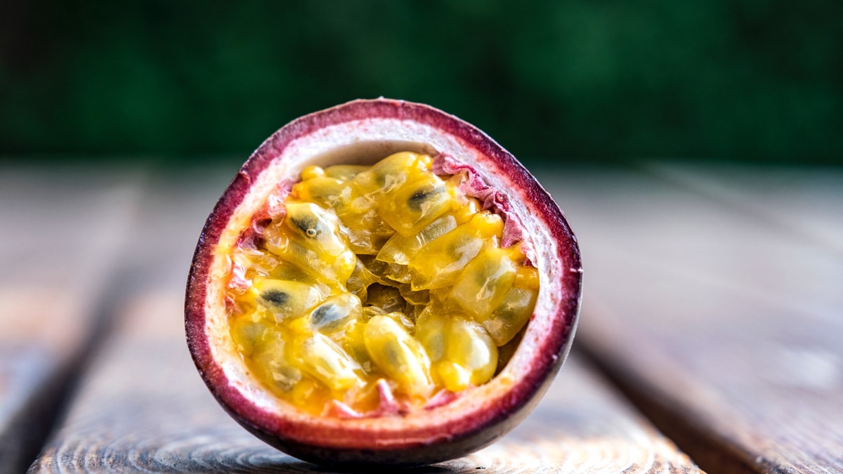 A front view of a single passion fruit cut in half.