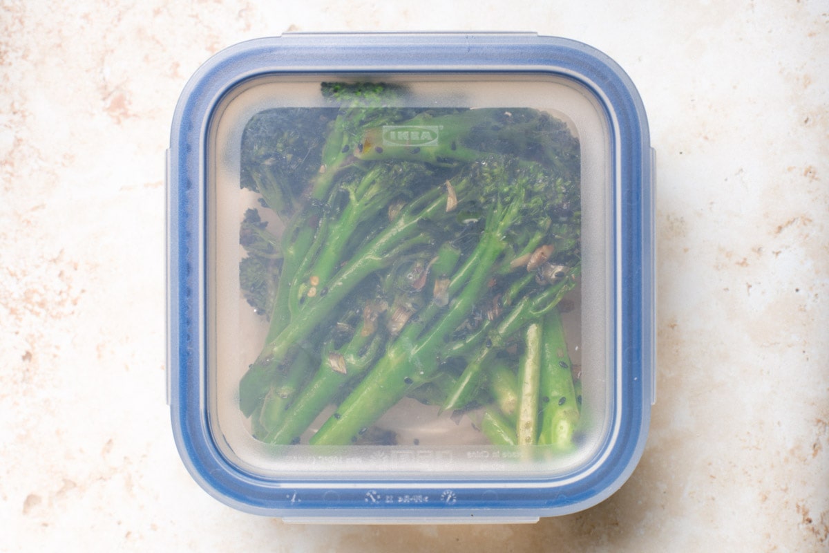 A plastic box containing leftover broccoletti. 