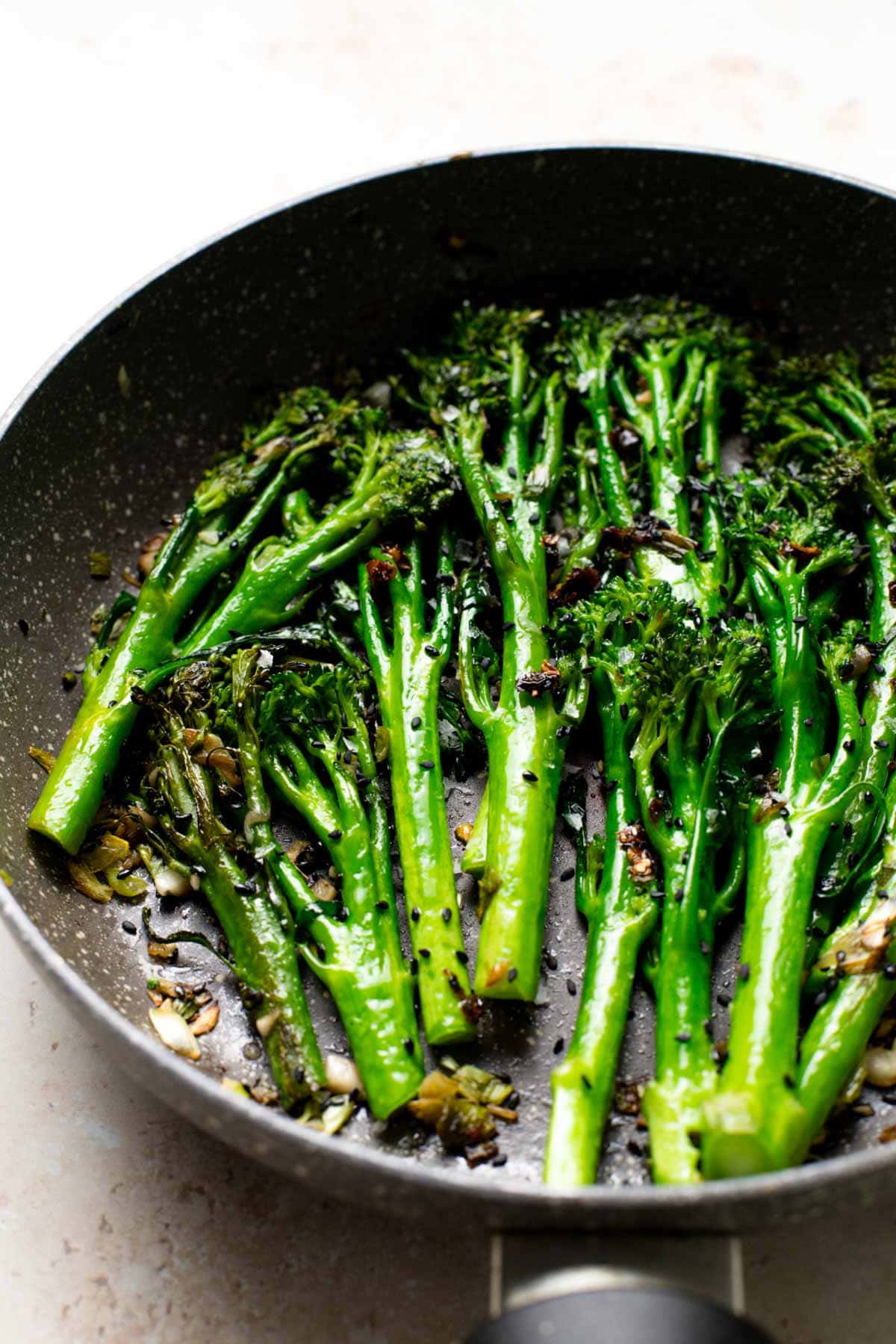 A frying pan containing cooked broccolini. 