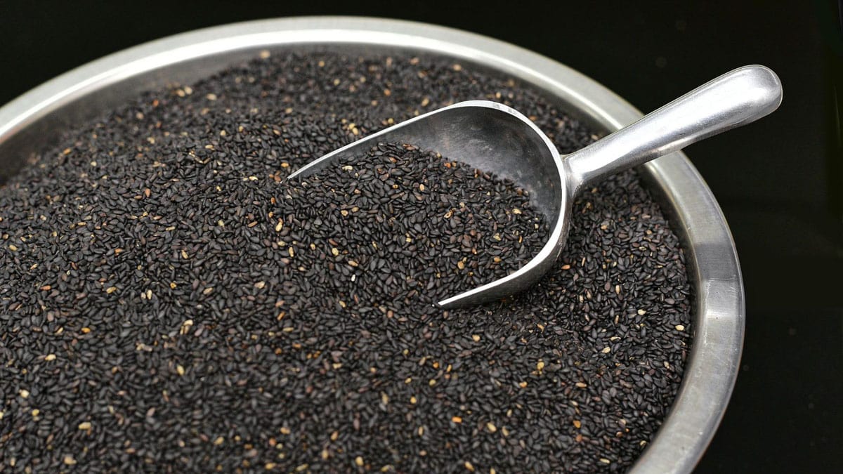 A large silver bowl containing black sesame seeds.