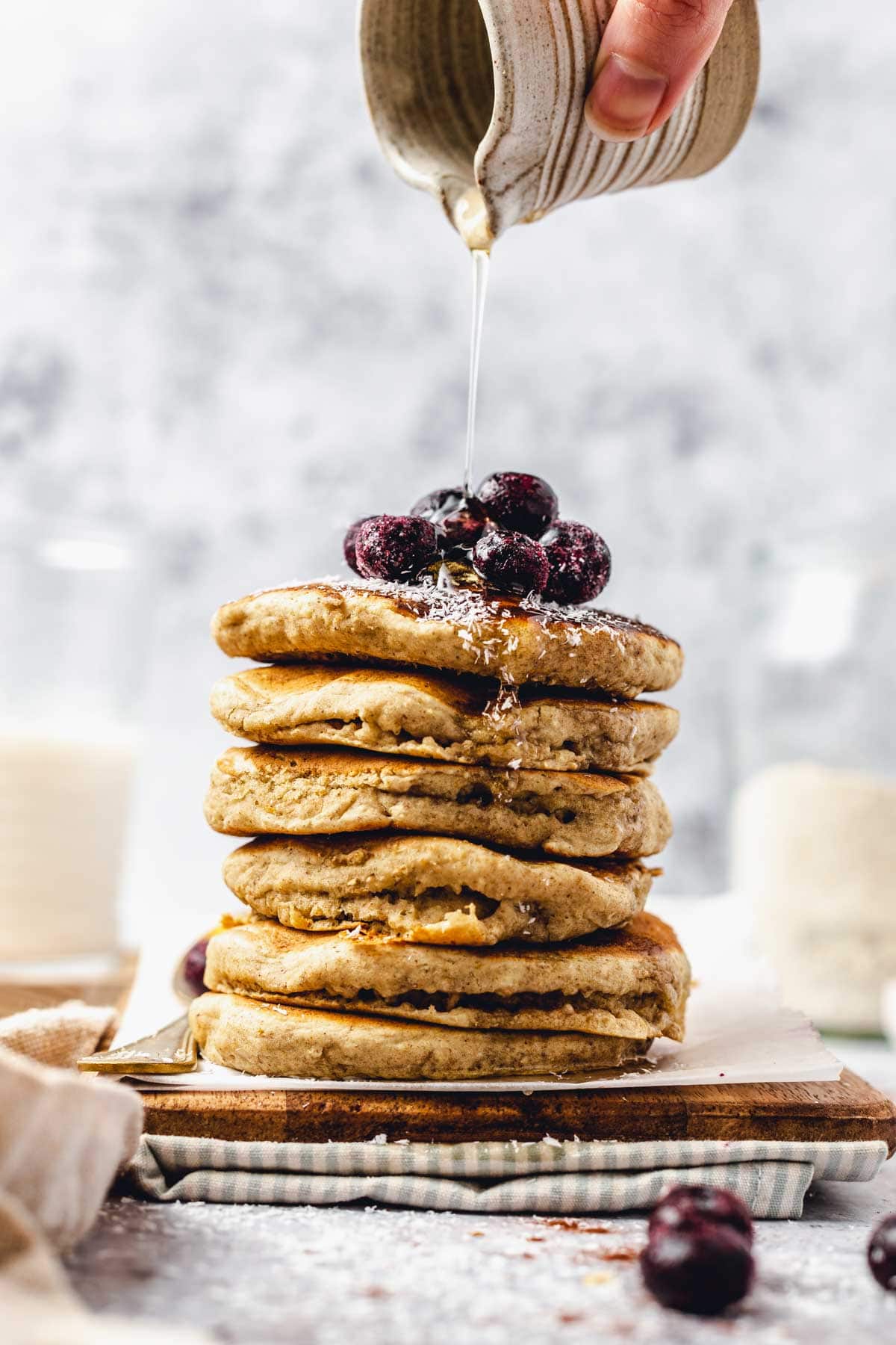 Syrup being poured over a stack of vegan pancakes.