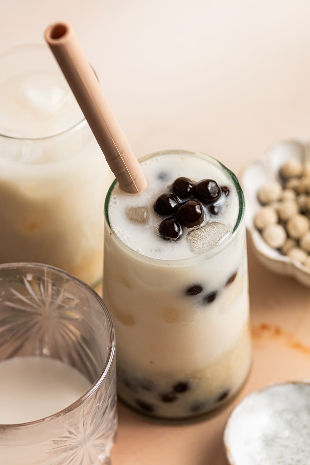 A side view of a glass of milk tea with black tapioca pearls. 