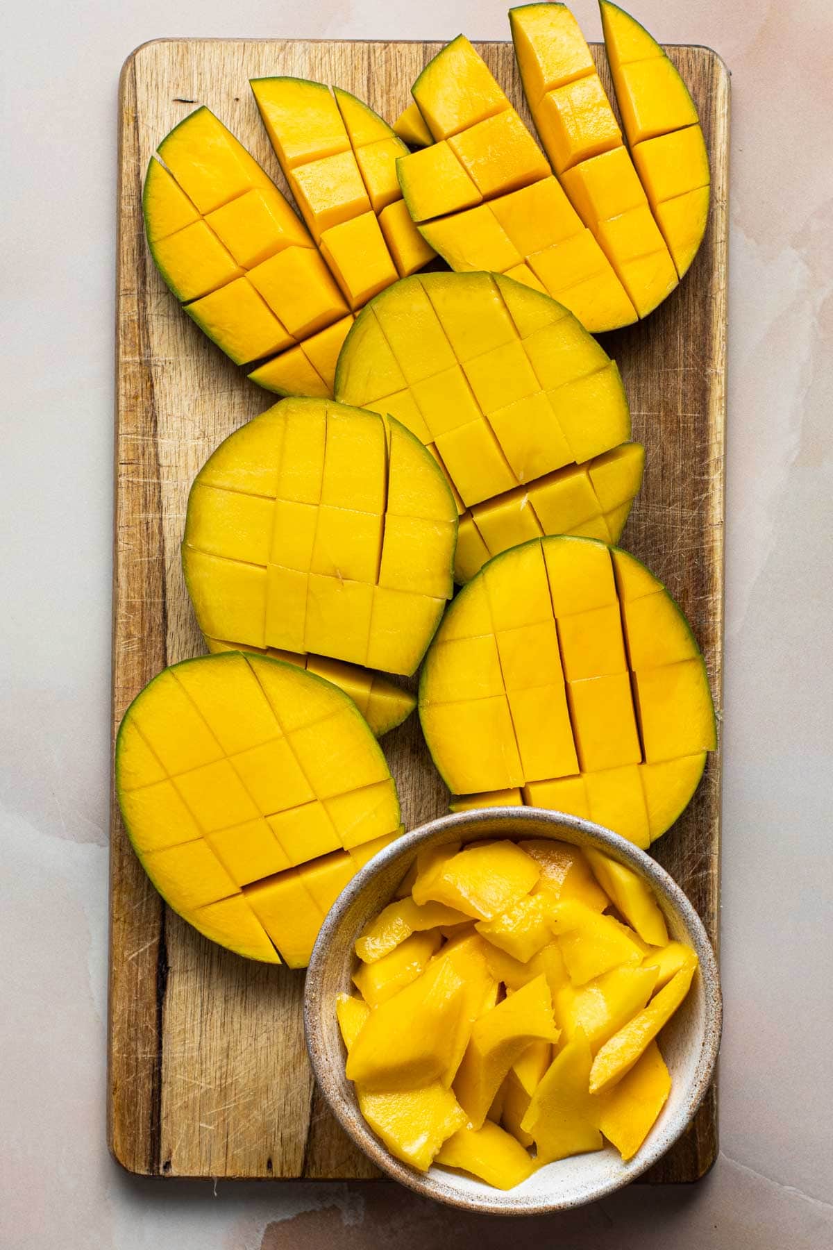 A chopping board featuring ripe and cut mango. 