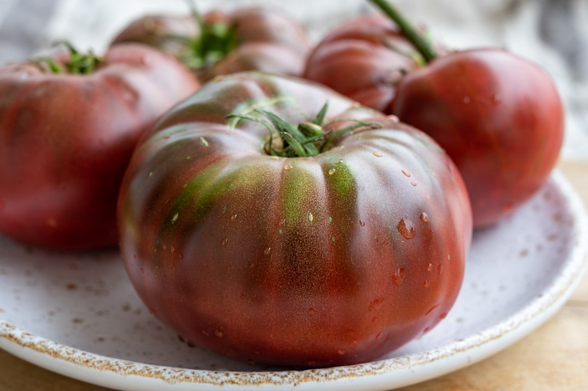 New harvest of big raddish-purple heirloom tomatoes close up.