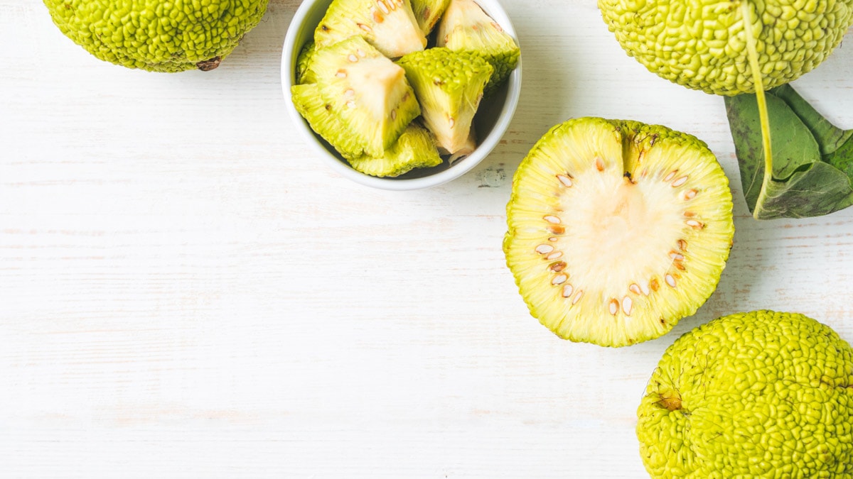 Green fruit osage orange on white wooden table.