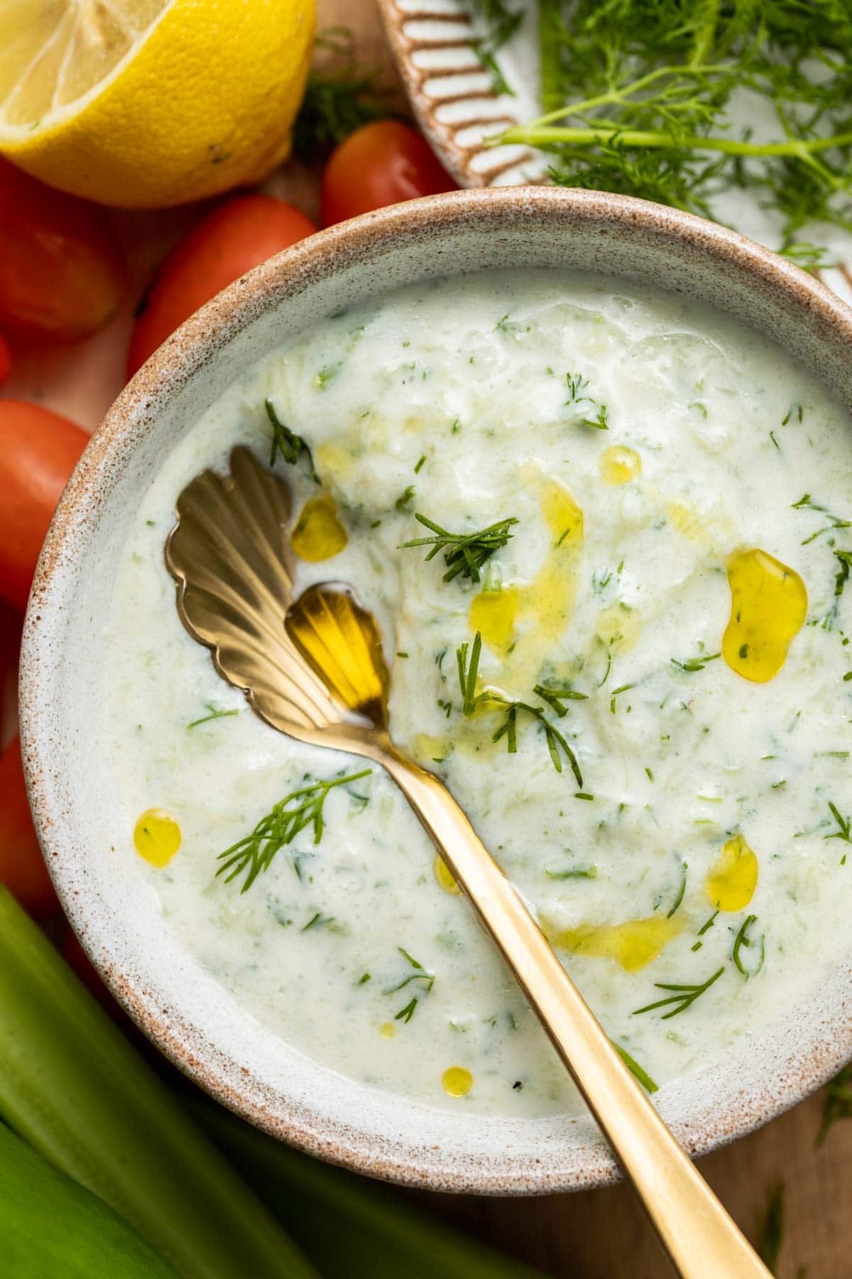 A bowl of tzatziki dip with a spoon in the middle. 