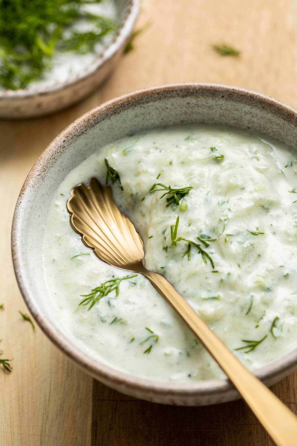 A bowl of tzatziki with a spoon in the middle. 