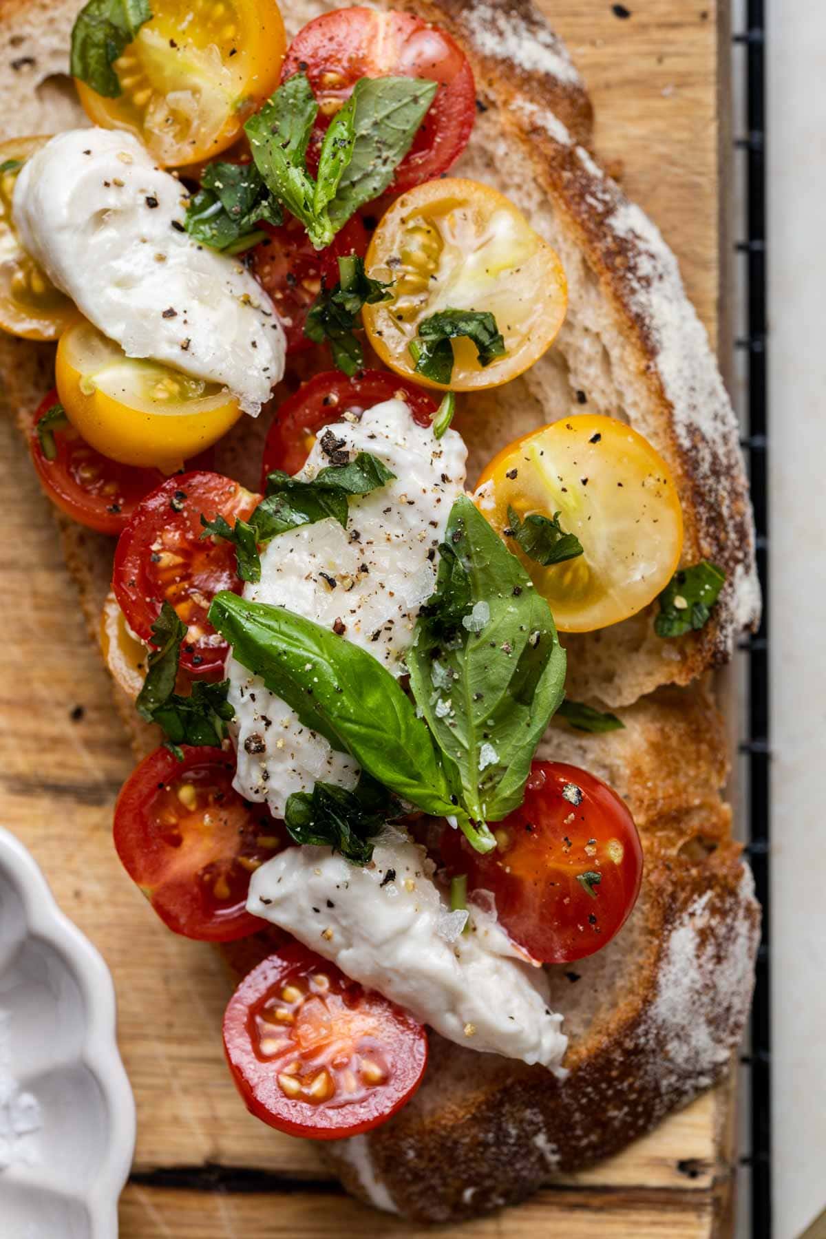 A close-up overhead view of toasted sourdough with tomatoes, cheese & basil. 