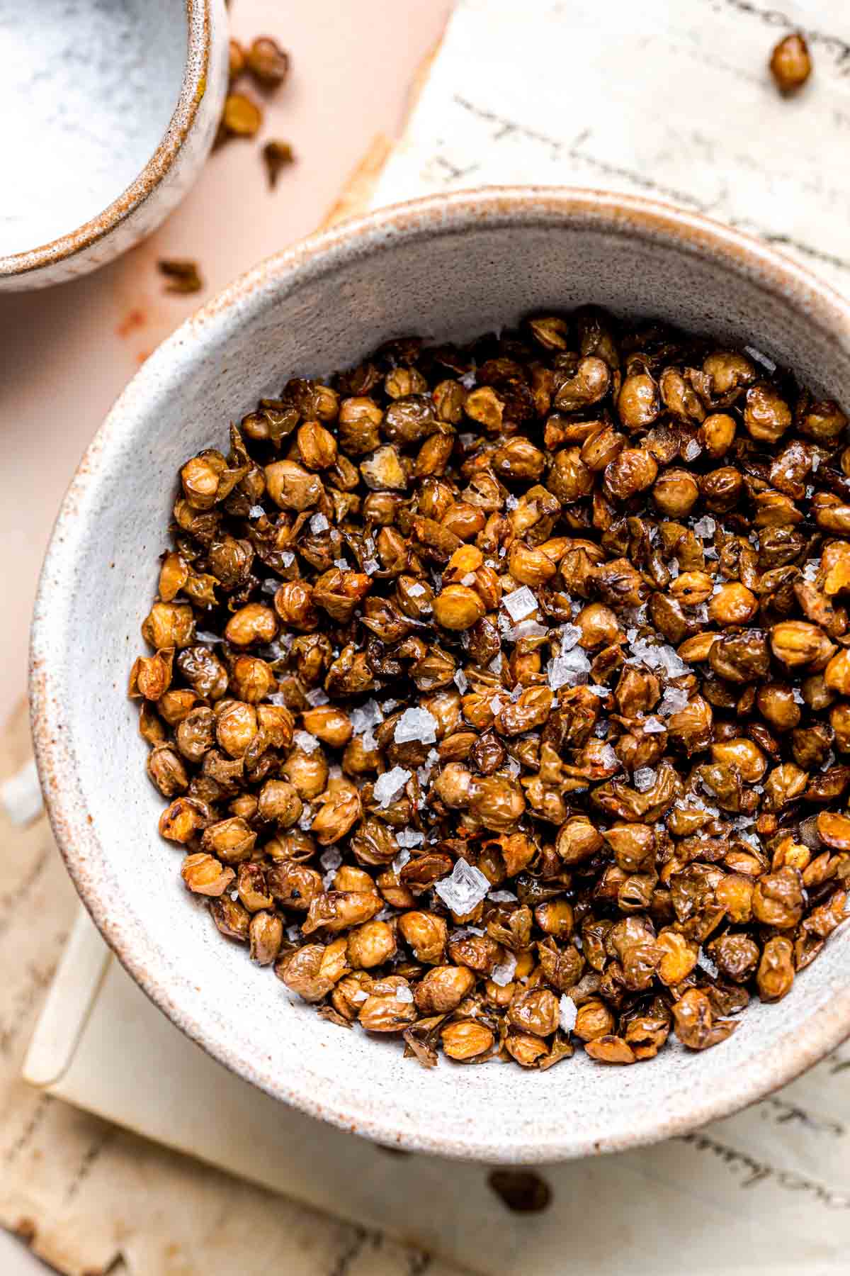 A bowl of roasted lentils topped with sea salt flakes.