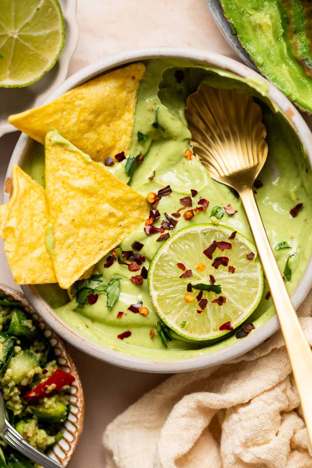Overhead image of avocado crema with lime, chili flakes and chips. 