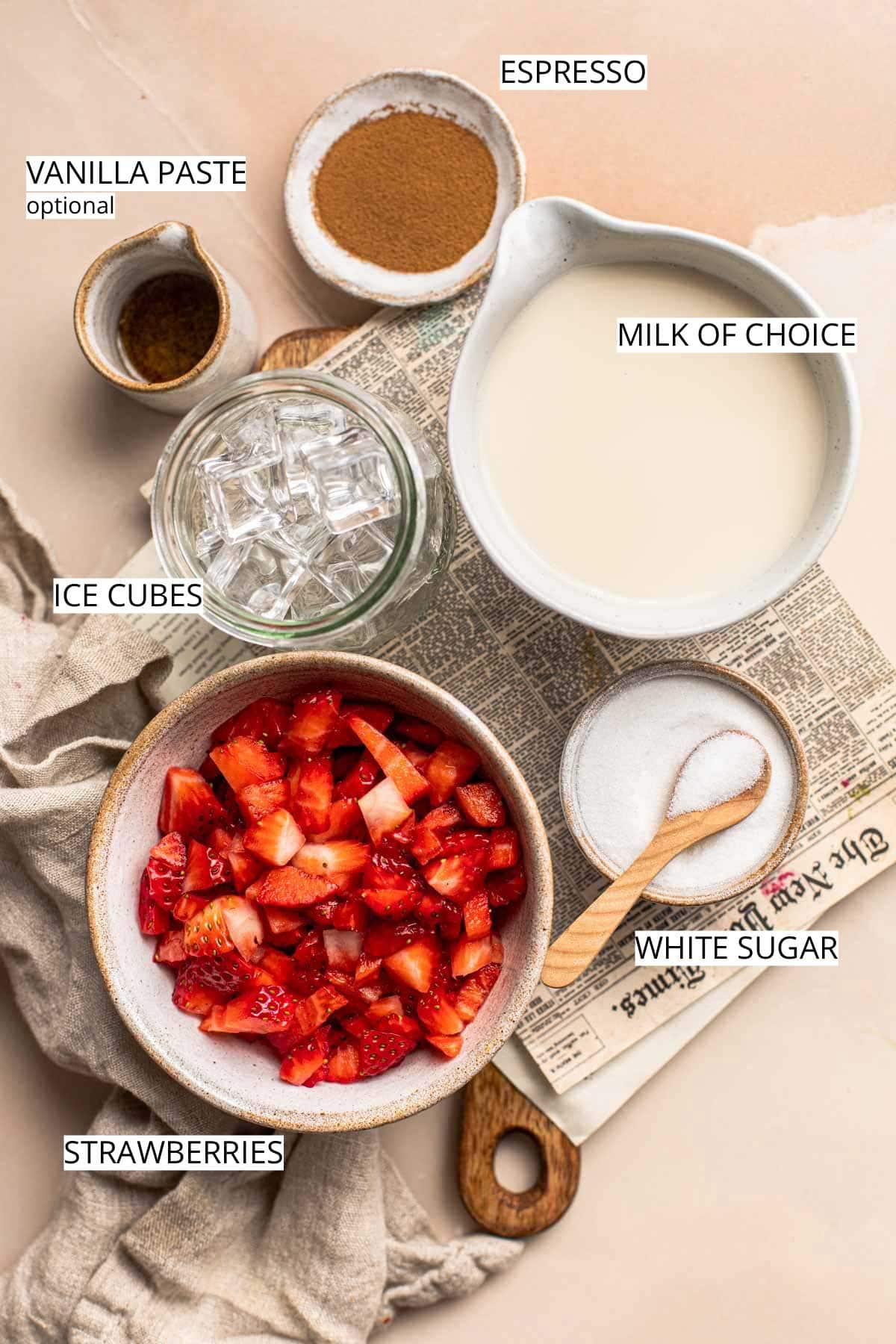 Strawberries, sugar, milk, vanilla & espresso on a flat surface.