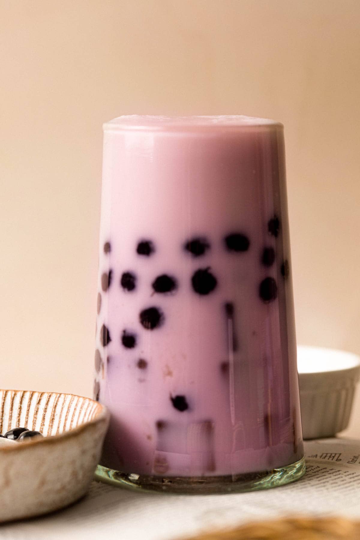 A side view of taro milk bubble tea in a tall glass.