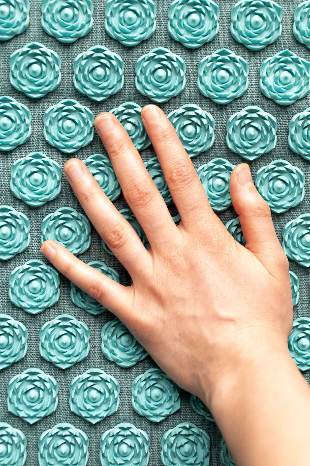 A hand pressing down on an acupressure mat.