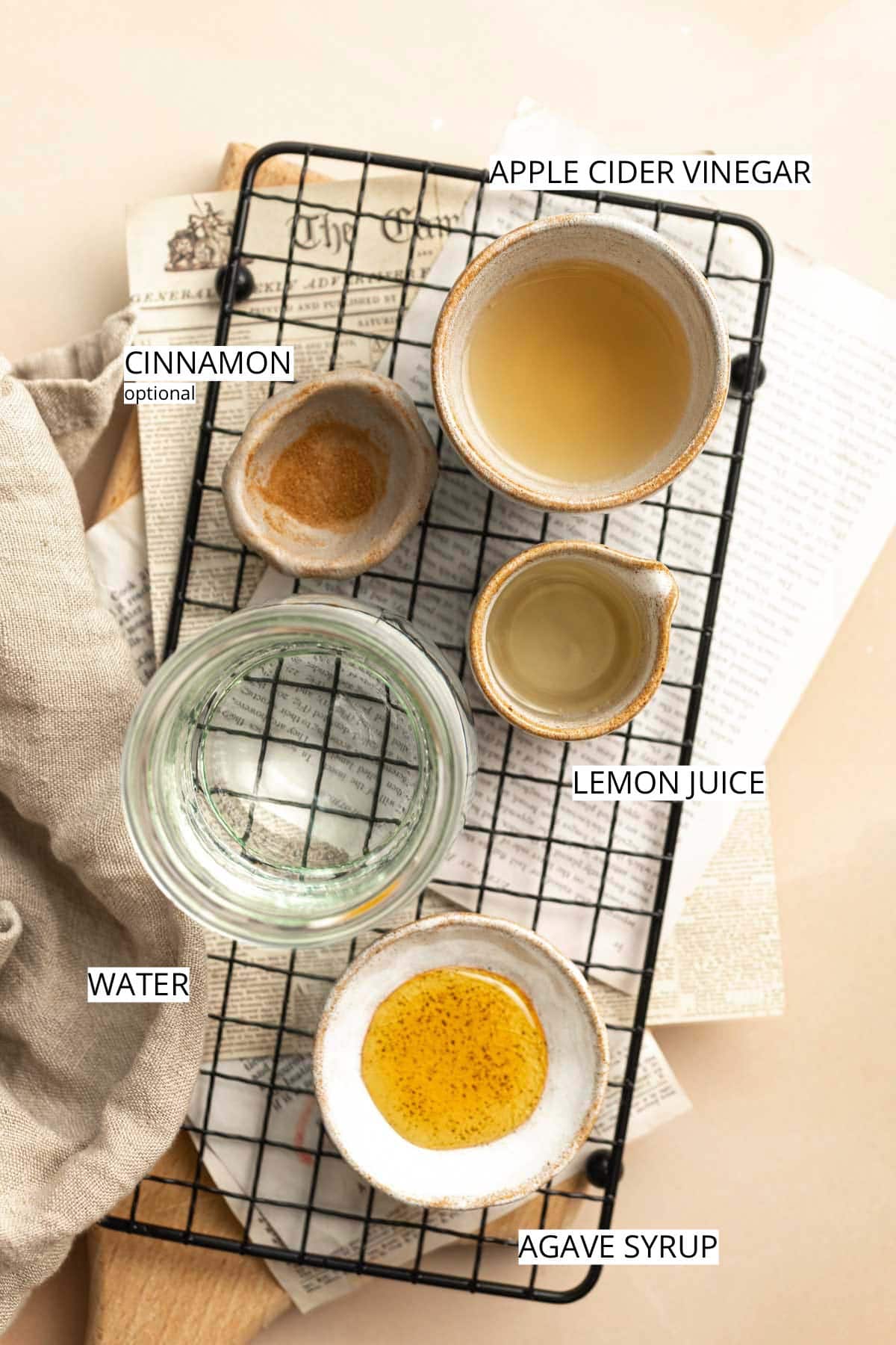 Apple cider vinegar, cinnamon, lemon juice, water and agave syrup laid out on a flat surface.