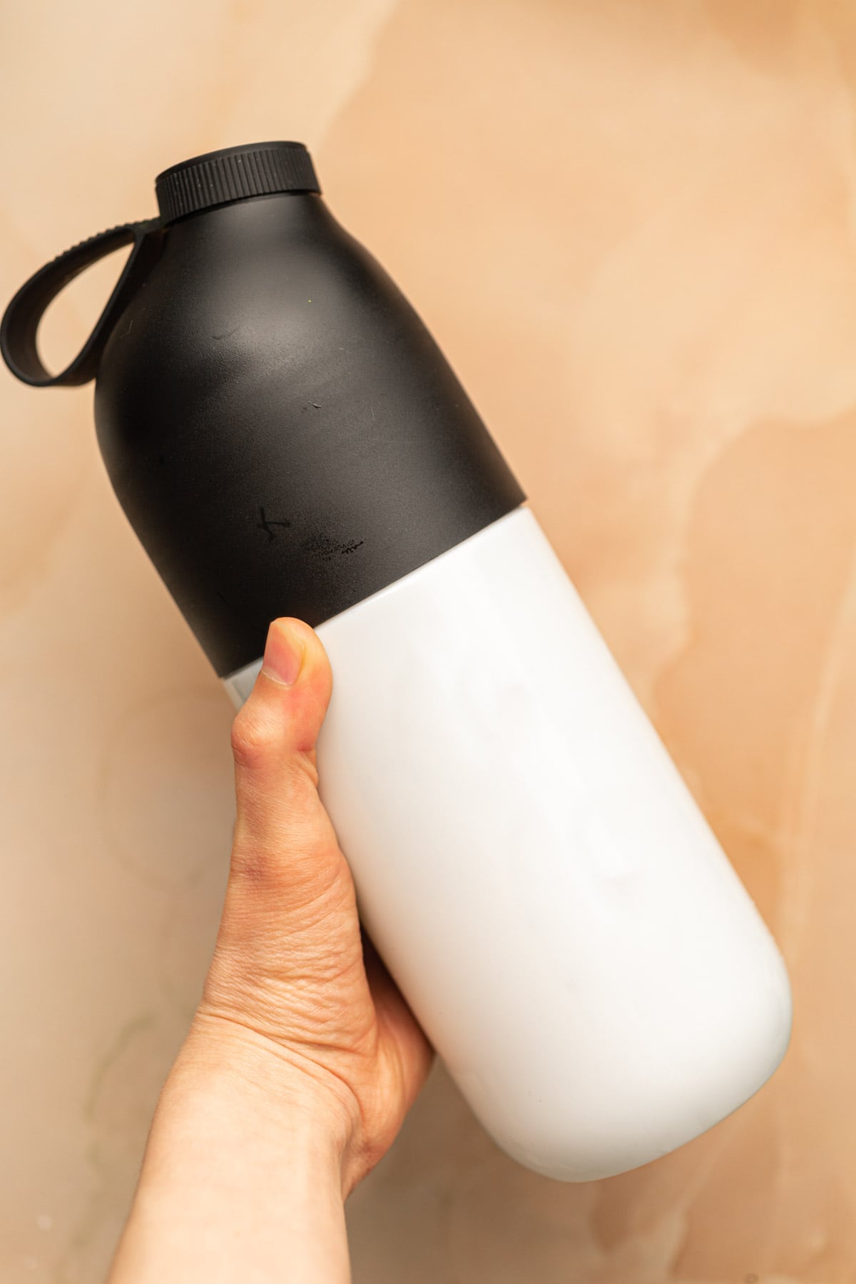 A hand holding out a shaker bottle.