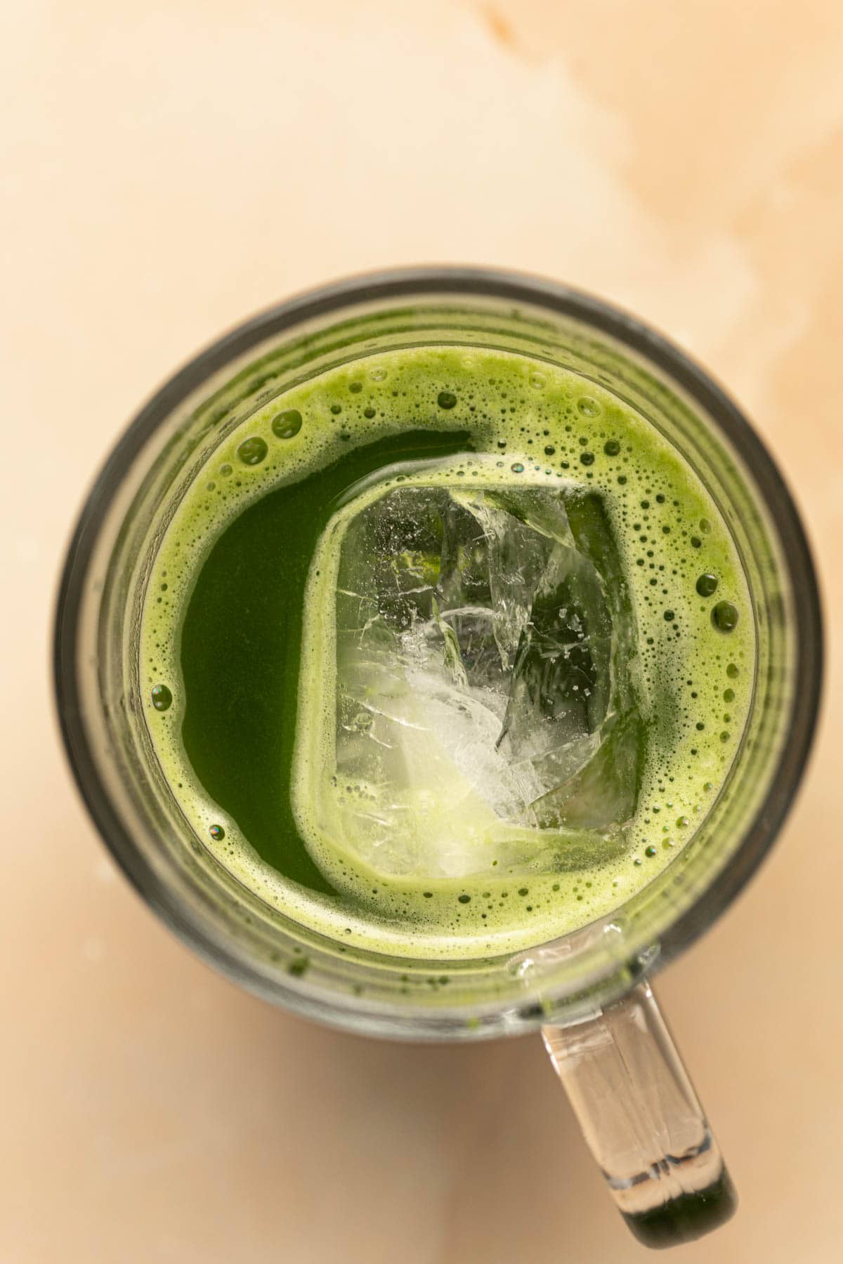 A glass of cold brew matcha with a large ice cube in the centre.