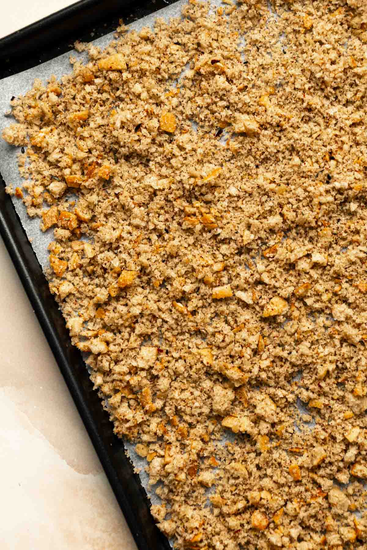 Breadcrumbs laid out on a lined baking sheet before baking.