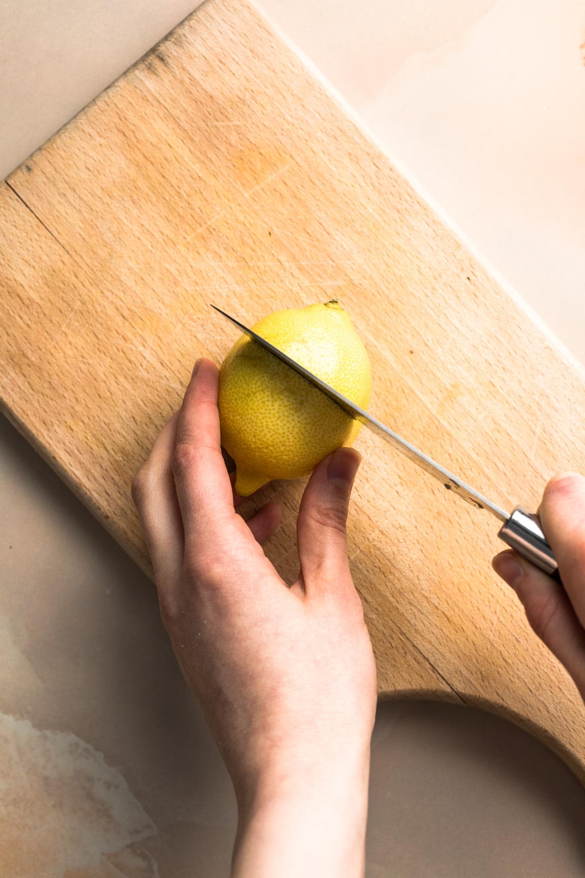 Lemon being sliced in half with a knife.