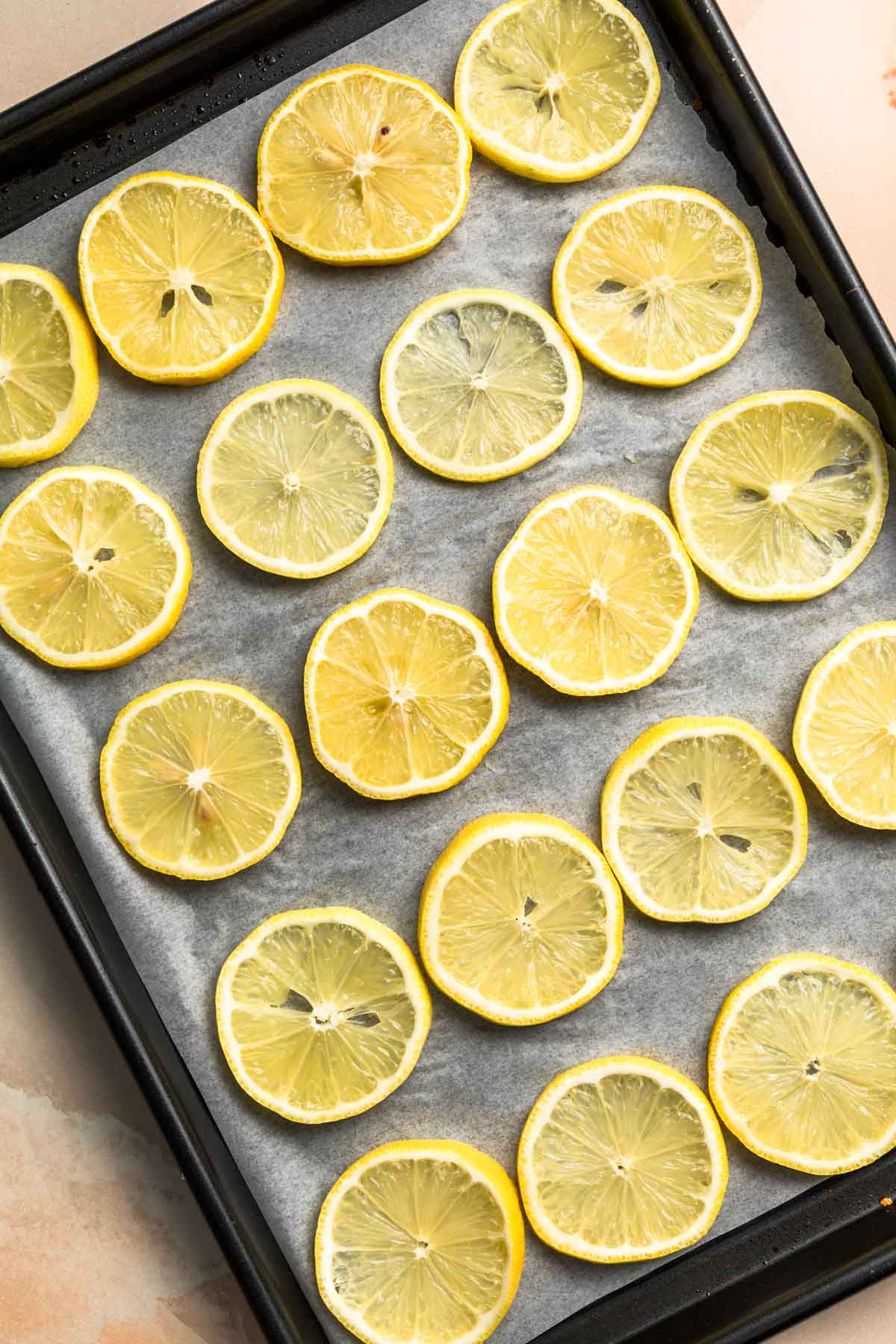 Fresh lemon slices arranged on a lined baking paper.