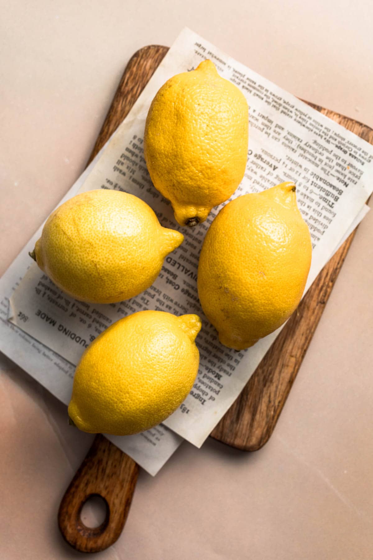 Four whole lemons on a chopping board.
