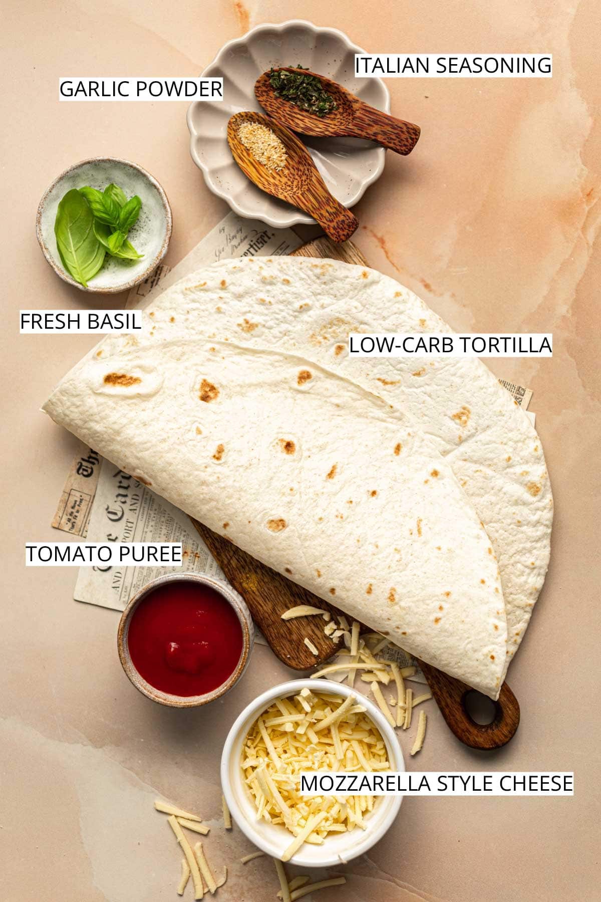 All ingredients to make crispy tortilla pizza laid out on a surface.