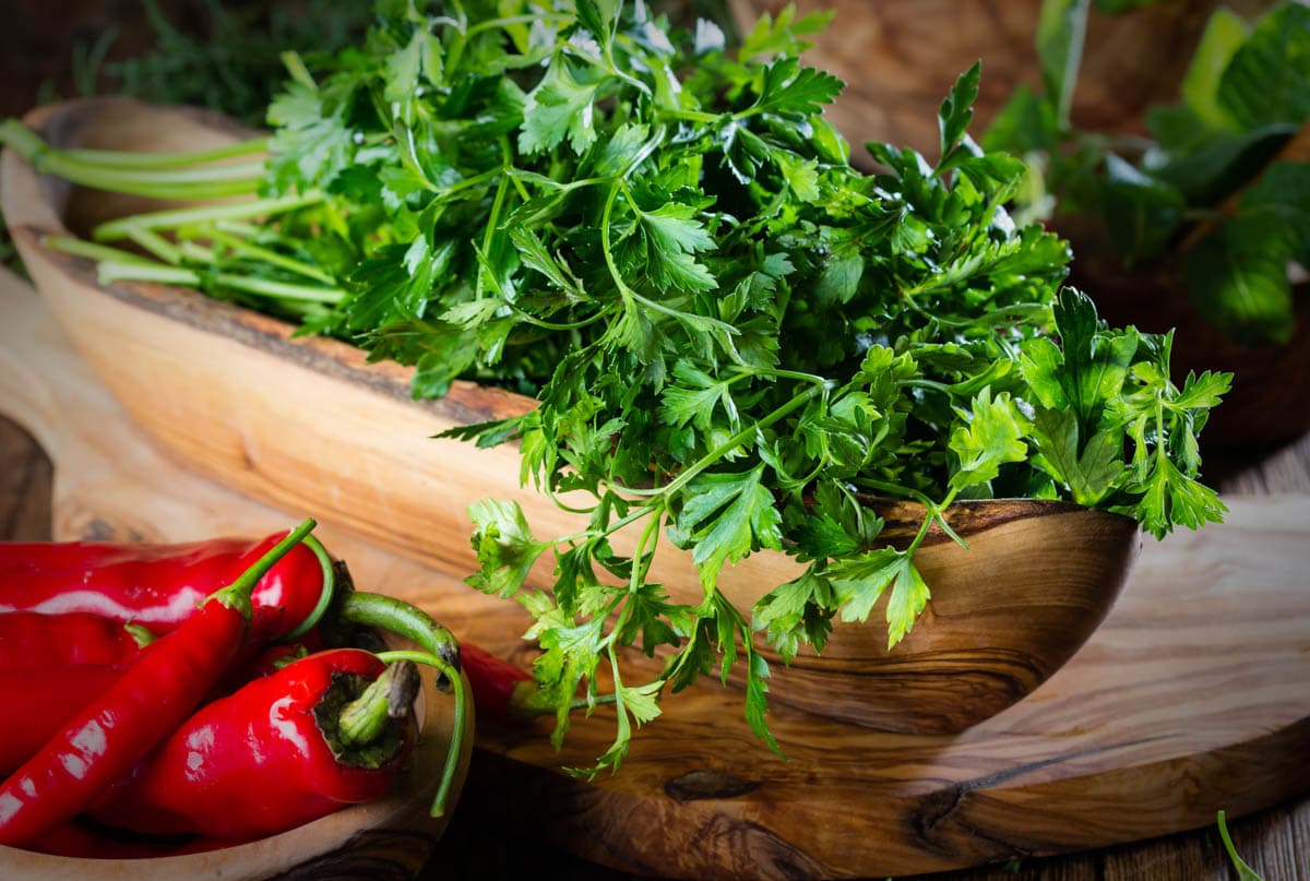 Fresh parsley in olive wooden bowl, wooden background