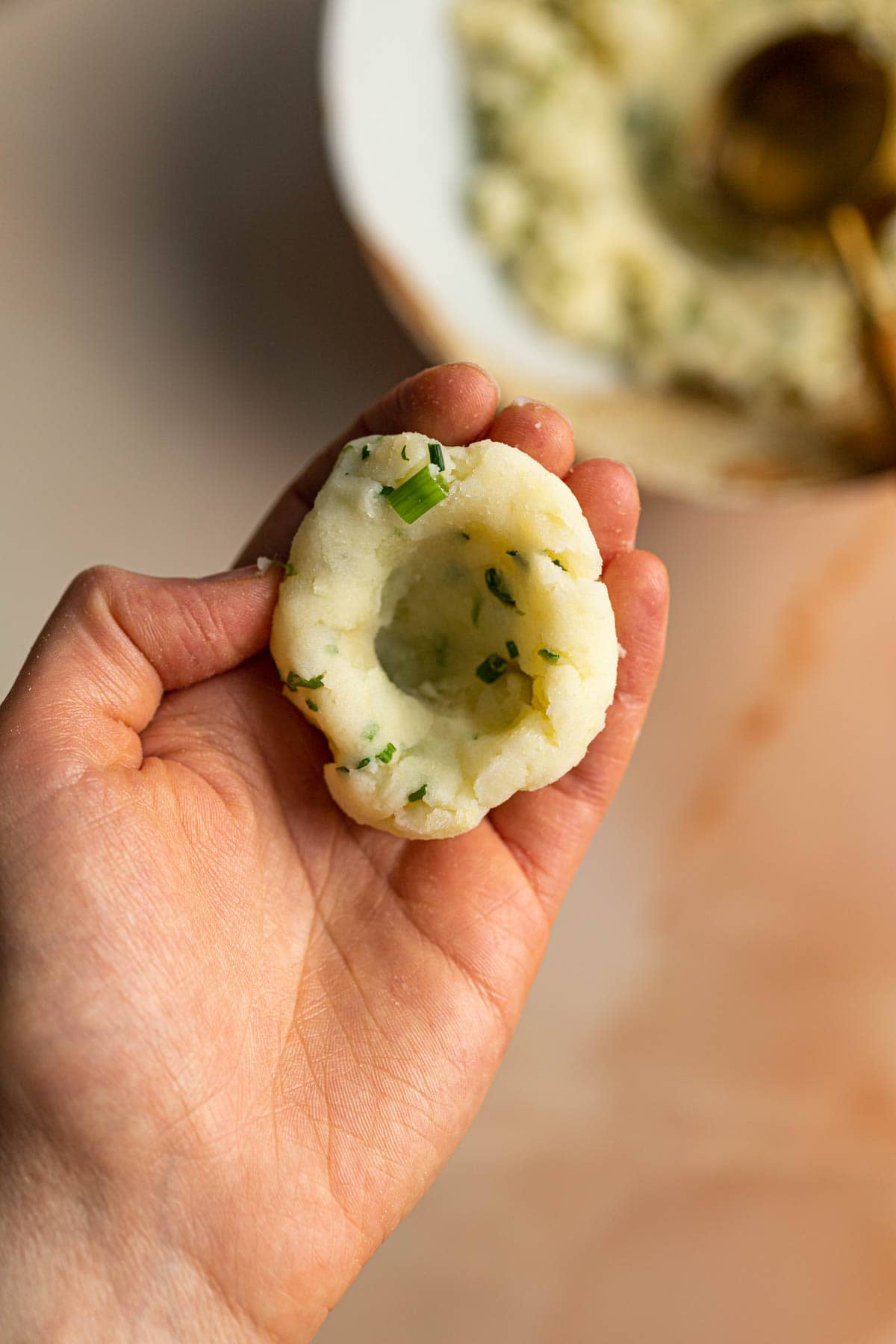 A hand holding out potato mochi dough.