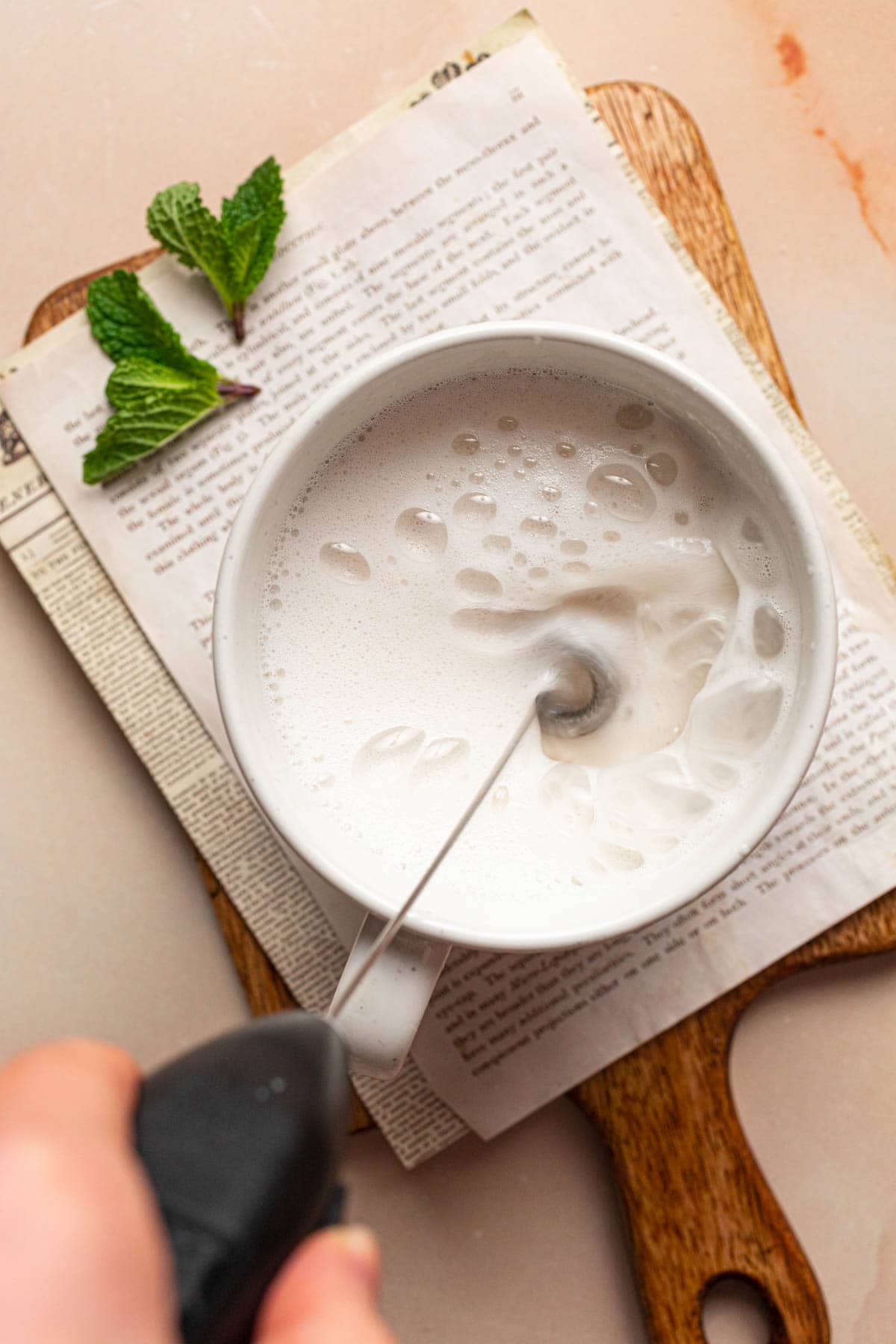 Oat milk being frothed using a handheld milk frother.