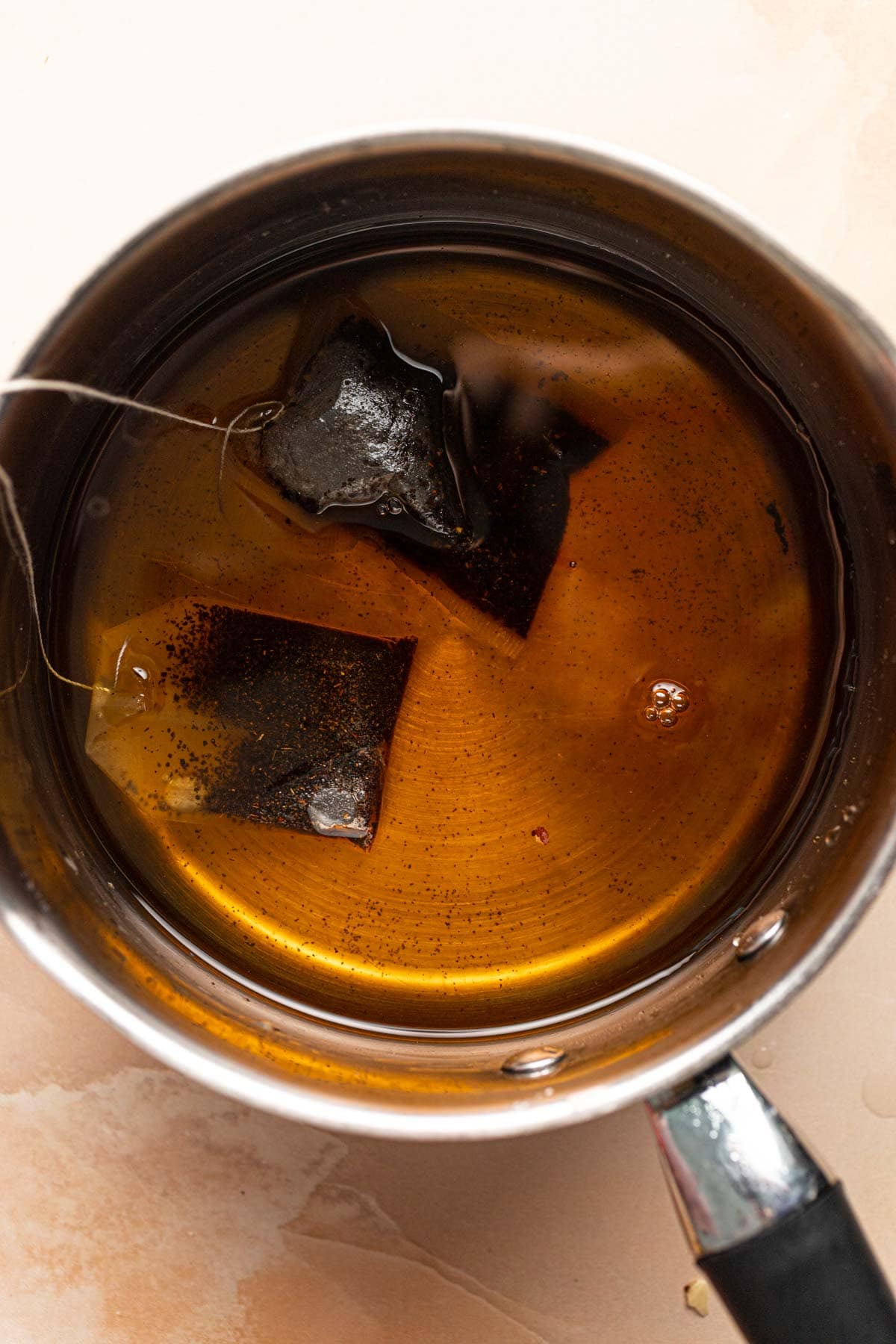 Two teabags steeping in water in a small saucepan.