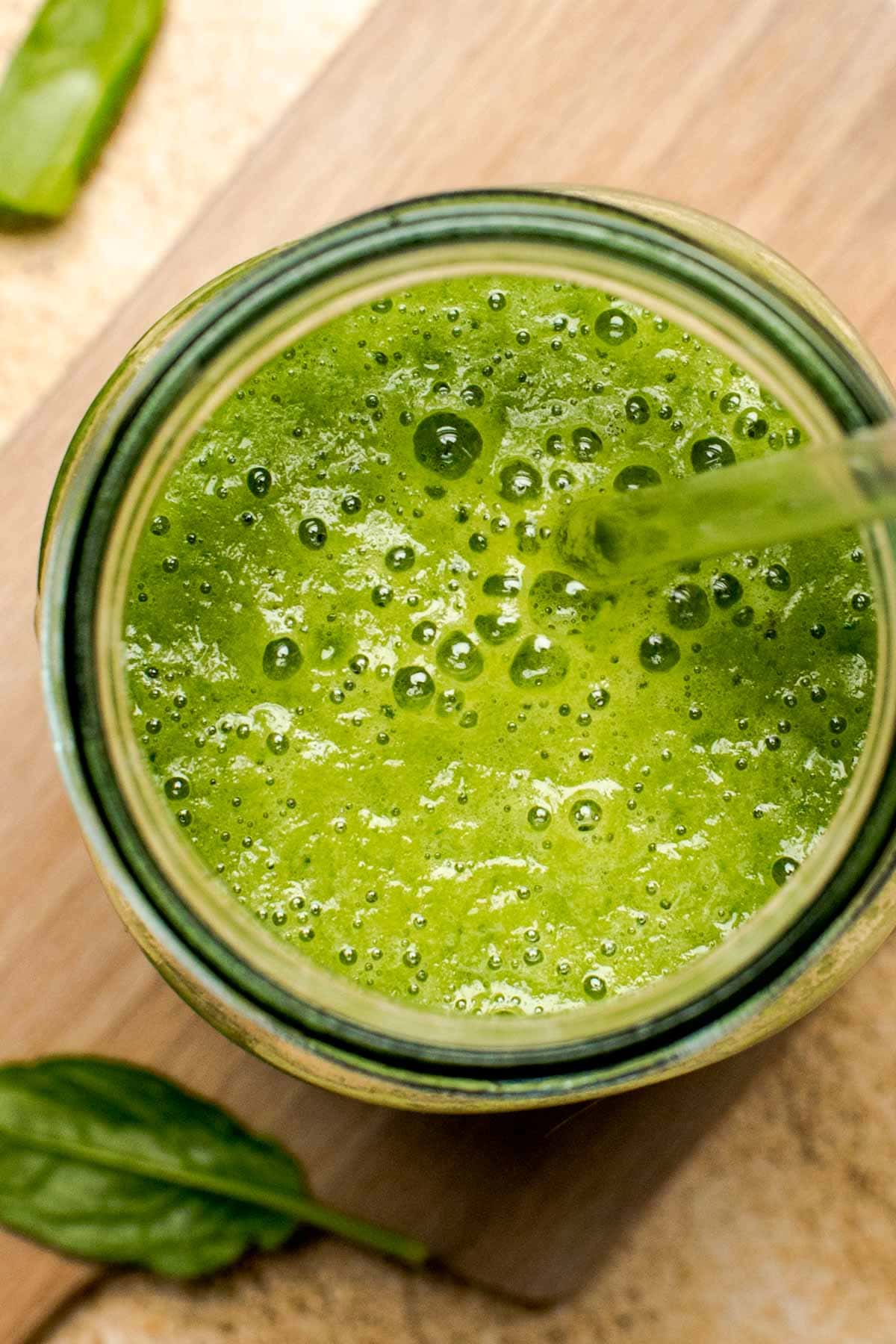 A close-up overhead view of green smoothie in a glass.