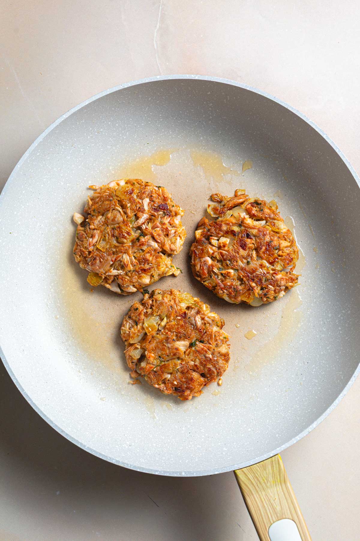 Three fried jackfruit burgers in a pan