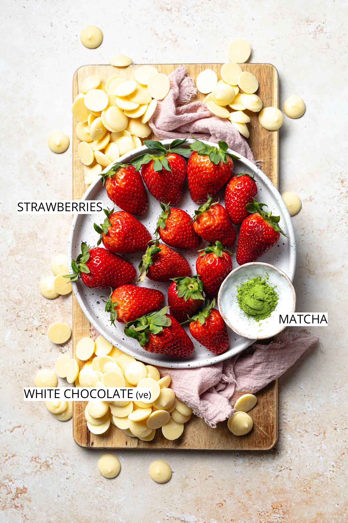 Strawberries, white chocolate buttons and matcha on a wooden board.