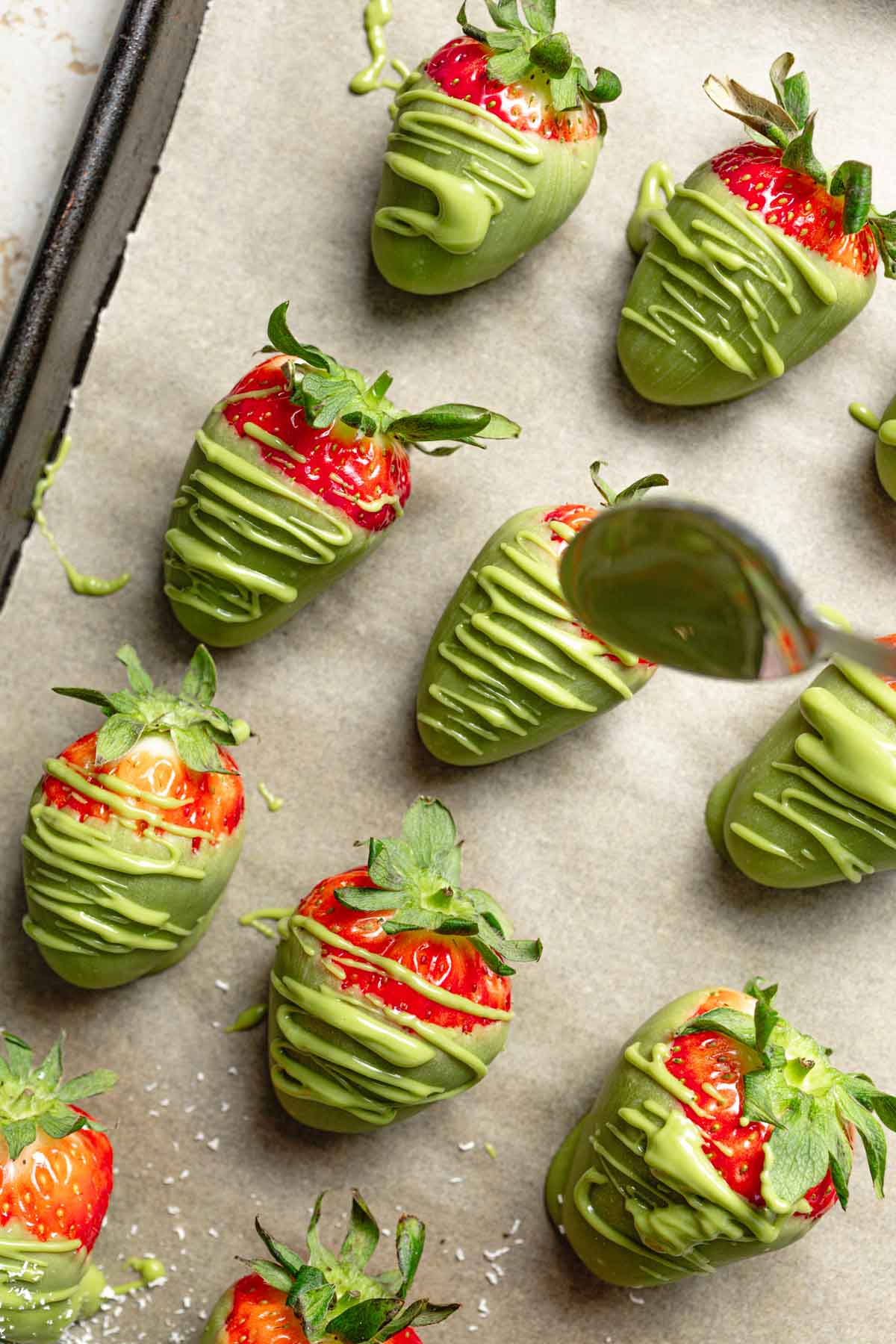 Glazed matcha strawberries being drizzled with white chocolate