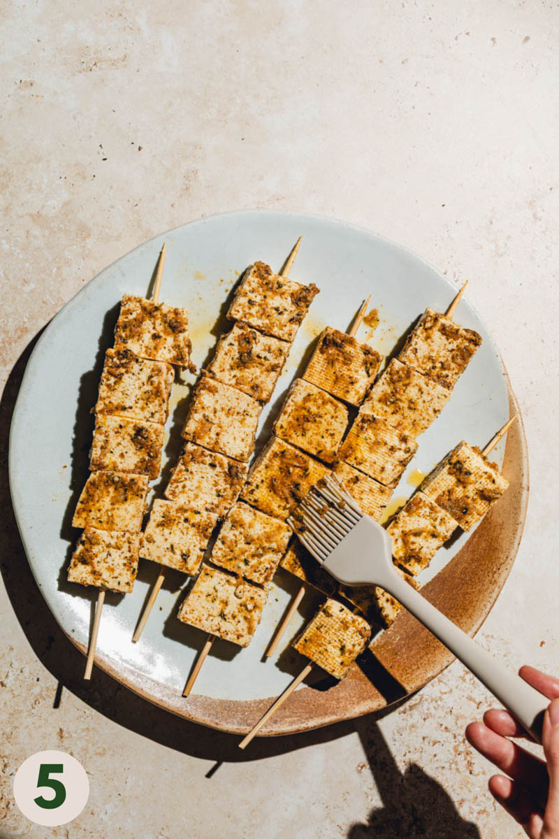 Extra marinade being brushed onto tofu cubes