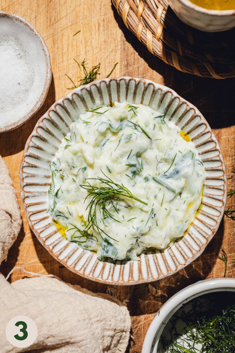 Vegan tzatziki topped with dill in a small bowl