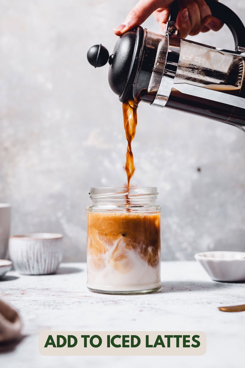 Coffee being poured into a glass of milk to make a latte