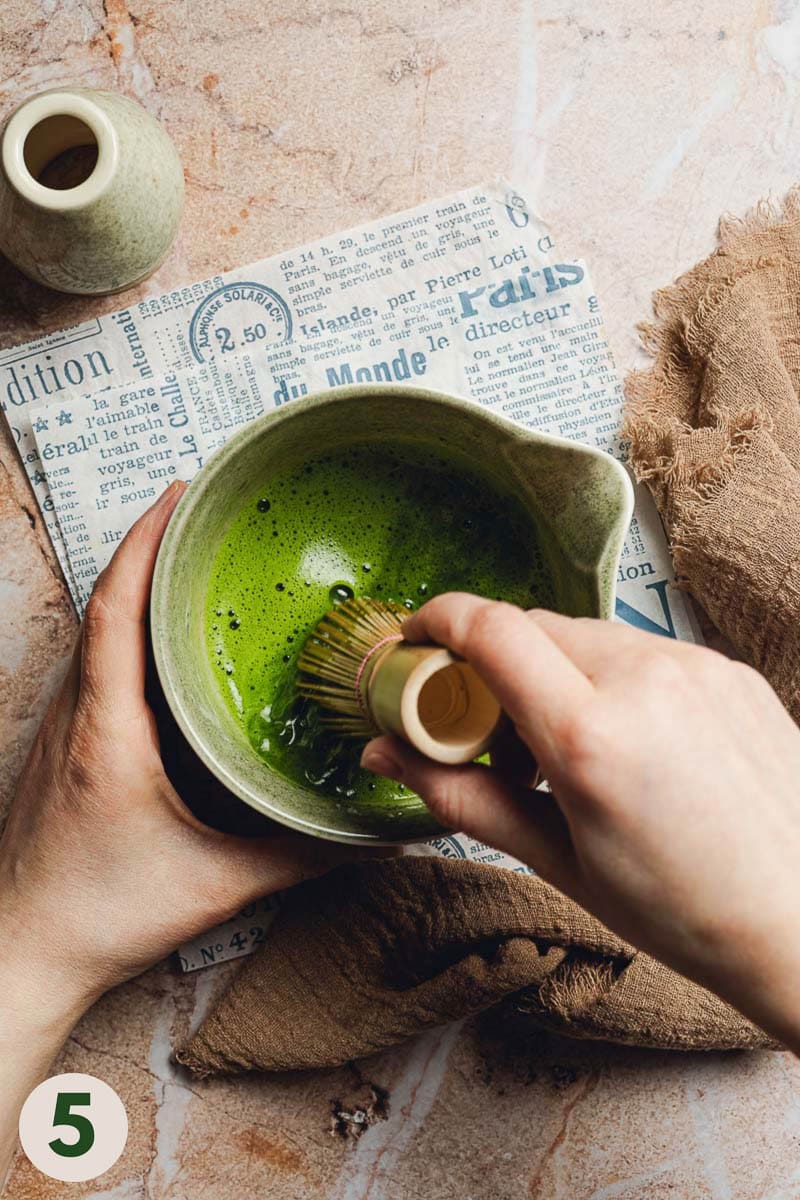 Hands whisking matcha in a bowl