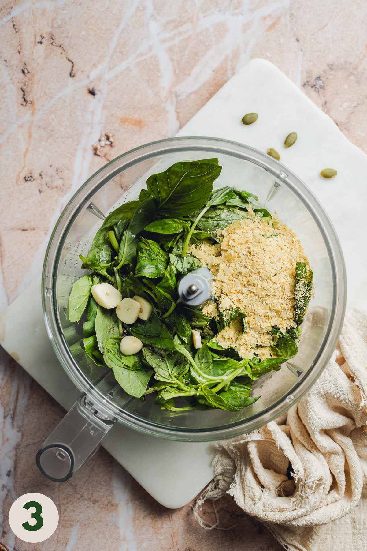 A food processor with pesto ingredients before blending